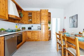 A kitchen with wooden cabinets, a dishwasher, a microwave, and a dining area with a table and chairs.