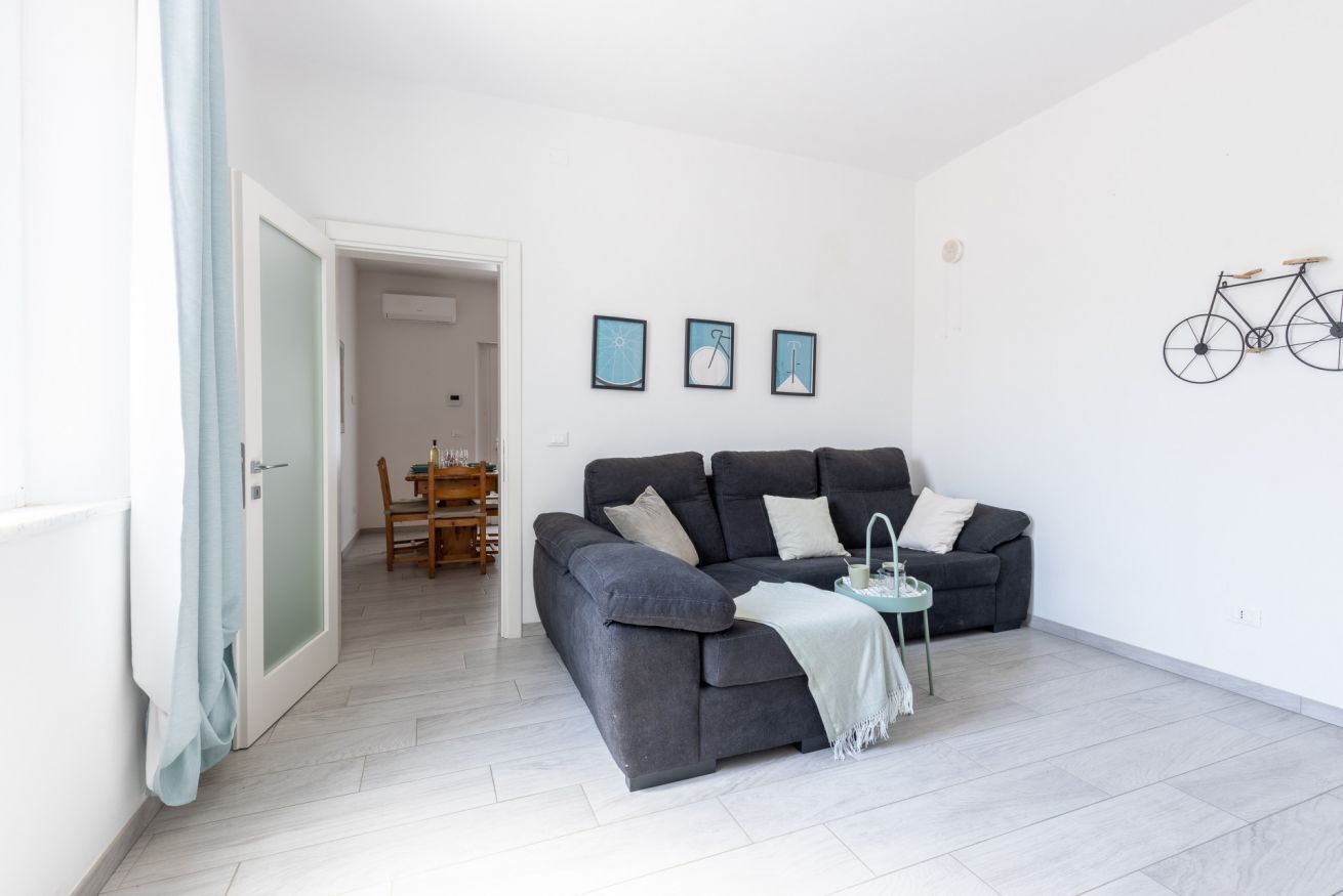 Una sala de estar moderna con un sofá gris, una mesita y una bicicleta colgada en la pared.