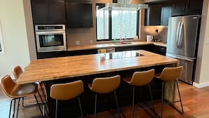 A modern kitchen with a large island, stainless steel appliances, and a window providing natural light. - Private Mountain Top Escape  with Hot Tub, Theater, Game Room & Fire Pit (Marshall)