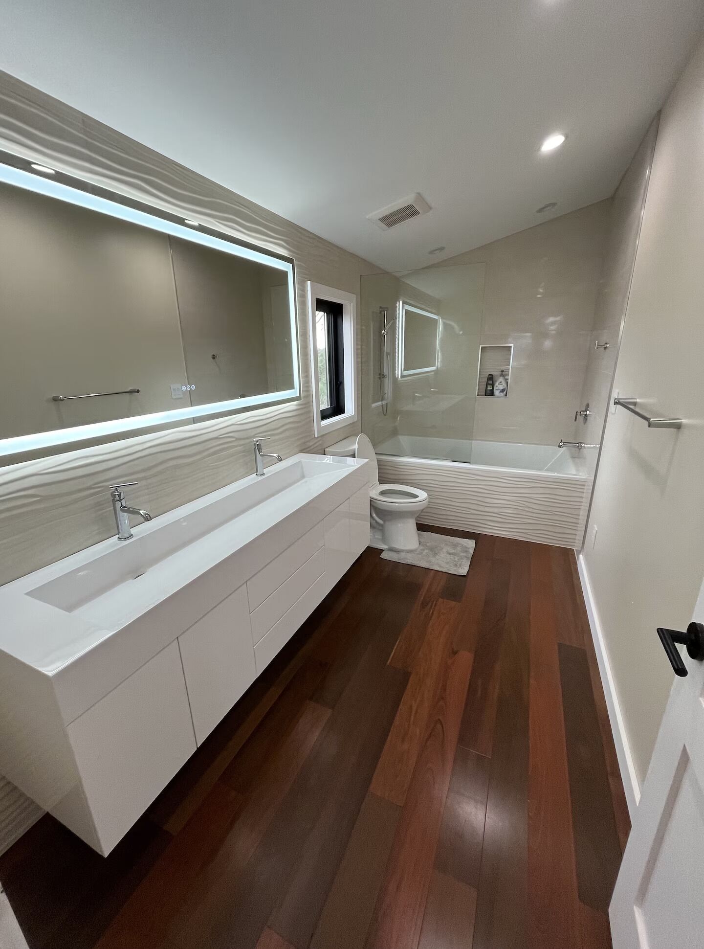 Un baño moderno con un lavamanos espacioso, ducha e inodoro.