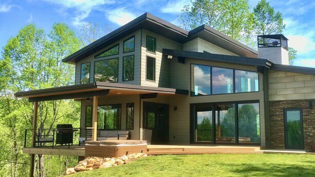 A modern two-story house with large windows, a covered patio, and a stone exterior. - Private Mountain Top Escape  with Hot Tub, Theater, Game Room & Fire Pit (Marshall)