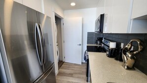 A modern kitchen with stainless steel appliances, a coffee machine, and a sink.