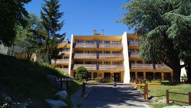Et hotel med flere etager, en gul facade, balkoner og et skilt med teksten "Le Moniikos".