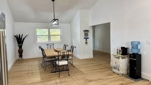 A spacious room with a wooden dining table and chairs, a water dispenser, and a large window.