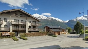 A hotel with a sign reading "Le Clos d'Aussois" in front of a mountain backdrop.