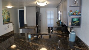 A kitchen with granite countertops, stainless steel appliances, and a built-in sink. - Desirable Ground Floor Direct Ocean Front End Unit (New Smyrna Beach)