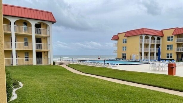 A hotel with a pool area, a beach view, and a well-maintained lawn. - Ocean View Ground Floor 2/2 (New Smyrna Beach)
