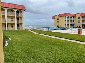A hotel with a pool area, a beach view, and a well-maintained lawn. - Ocean View Ground Floor 2/2 (New Smyrna Beach)