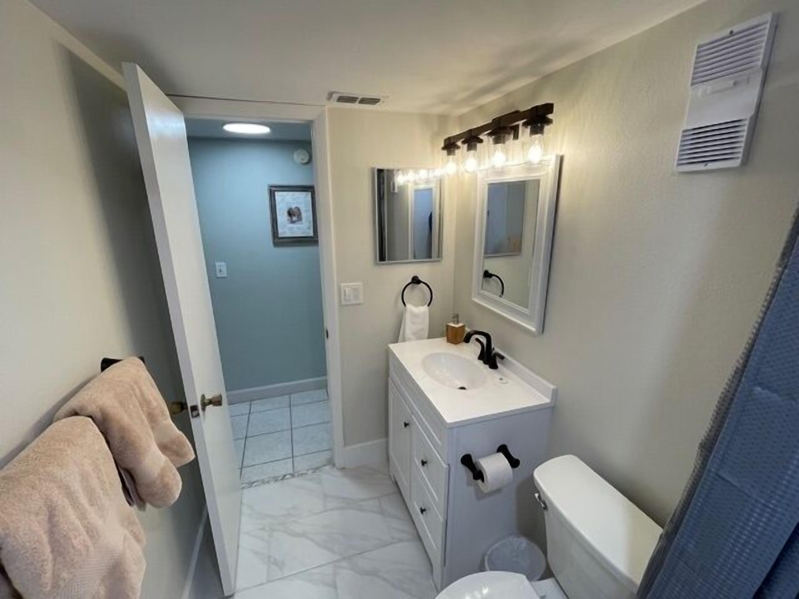 A bathroom with a white sink, a mirror, a toilet, and a towel rack.