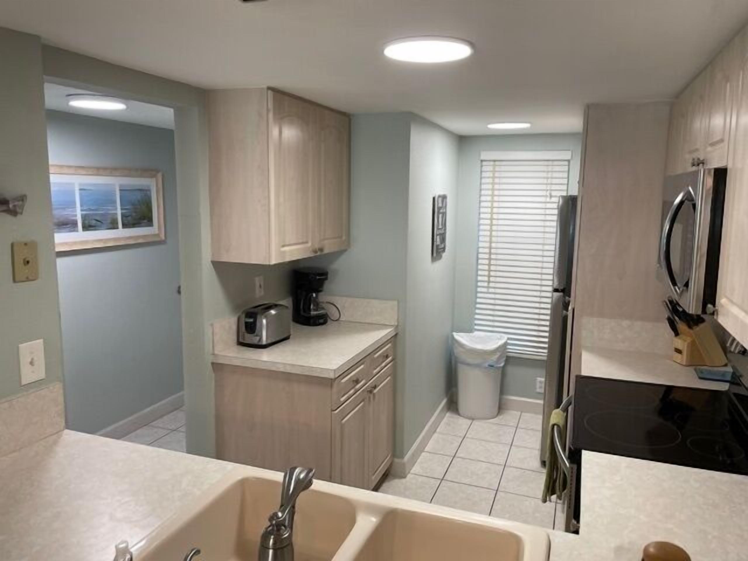 A compact kitchen with a double sink, a coffee maker, and a refrigerator.