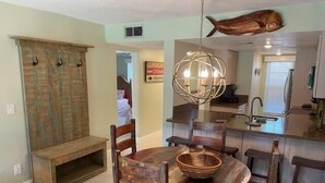 Ein Essbereich mit einem Holztisch und Stühlen, einer hängenden Leuchte und einer fischförmigen Dekoration an der Decke.