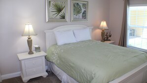 A bedroom with a bed, two bedside tables, and two wall-mounted lamps. - Ocean View Ground Floor 2/2 (New Smyrna Beach)