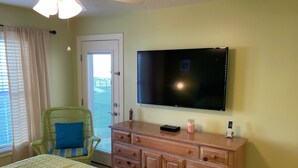 A bedroom with a bed, a dresser, a television, and a chair. - Ground Floor Ocean View 2/2 (New Smyrna Beach)