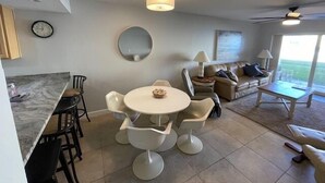 Un salón moderno con una mesa de comedor redonda, sillas blancas, un sofá y un ventilador de techo.