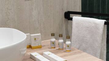 A bathroom with a large white sink, a wooden countertop, a towel rack with a white towel, and a wall socket.