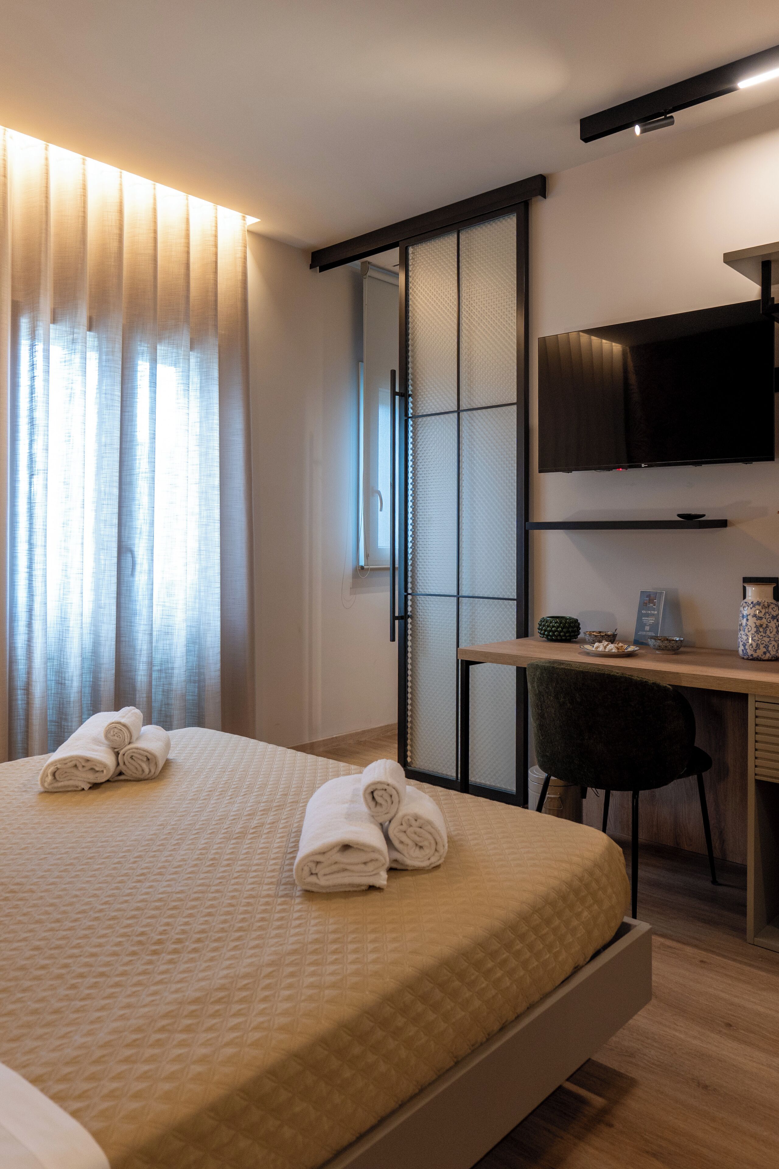 Ein modernes Hotelzimmer mit Bett, Schreibtisch, Stuhl und Fernseher.