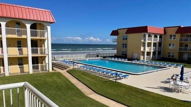 A hotel with a pool, a view of the ocean, and a well-maintained lawn. - Ocean View Second Floor 2/2 (New Smyrna Beach)