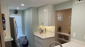 A compact kitchen with white cabinets, a sink, and a coffee maker. - Ocean View  Second Floor 2/2 (New Smyrna Beach)