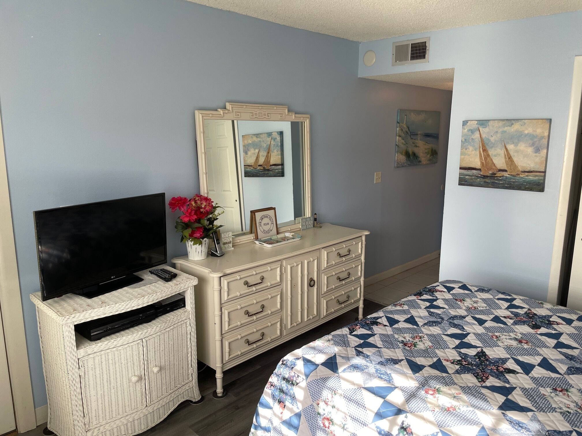 A bedroom with a TV, dresser, and bed.