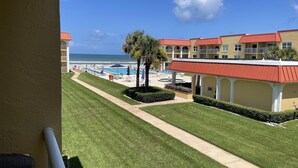 Ein Hotel mit Pool, Strandblick und gepflegter Rasenfläche.