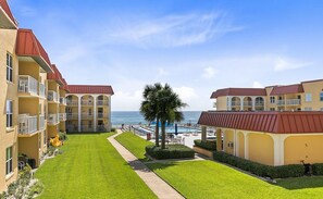 A resort with multiple-story buildings, a pool area, and a view of the ocean.
