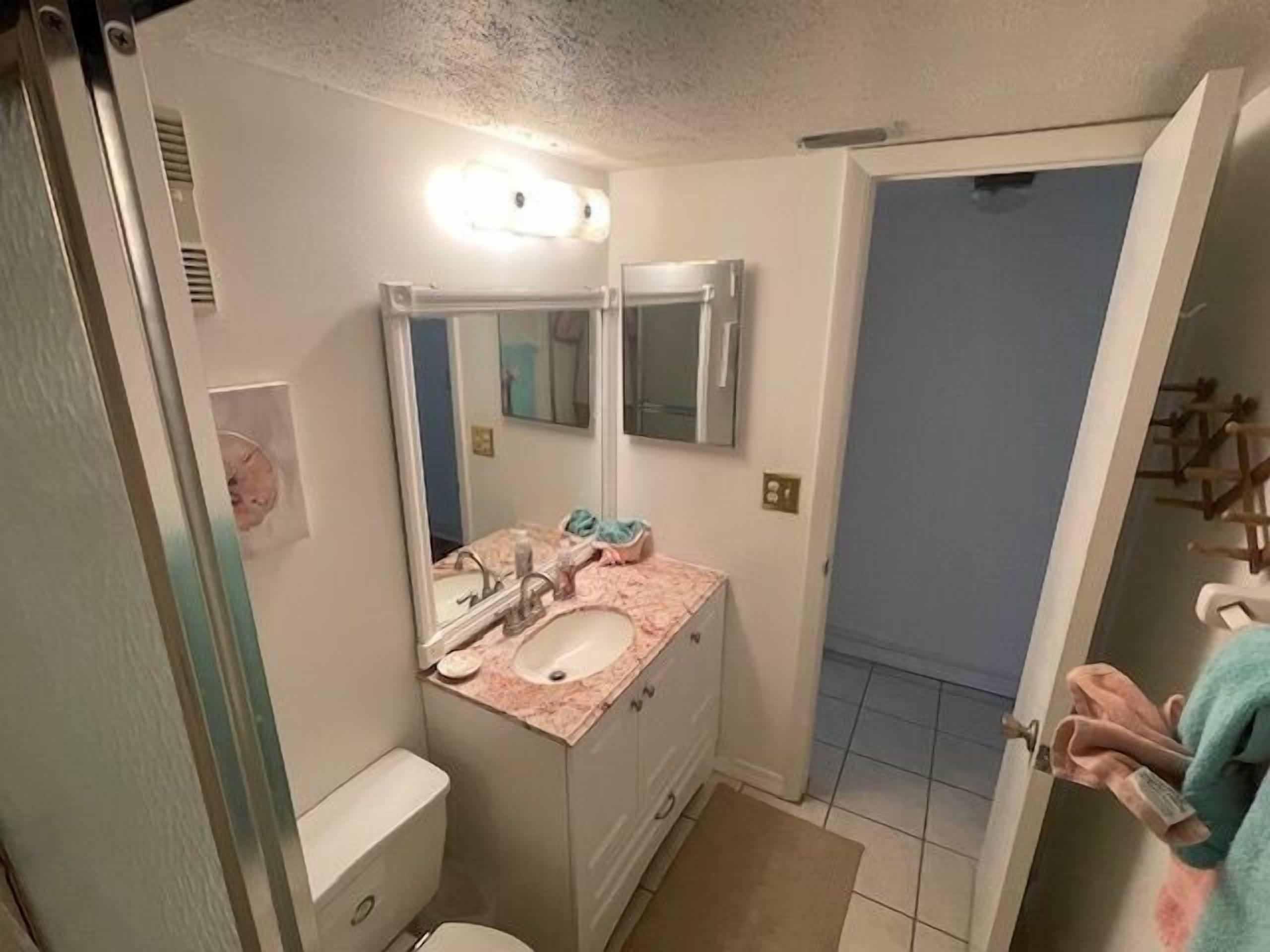 Un baño con lavamanos, espejo e inodoro.