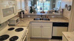 A modern kitchen with white cabinets, a stove, a dishwasher, and a sink. - Ocean View Second Floor 2/2 (New Smyrna Beach)