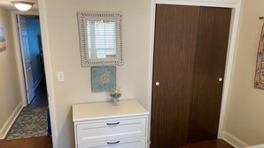 A bedroom with a white dresser, a mirror, a wooden door, and a blue door in the background. - Ocean View Second Floor 2/2 (New Smyrna Beach)