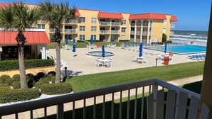 A hotel with a pool, outdoor seating, and a view of the ocean. - Ocean View Second Floor 2/2 (New Smyrna Beach)