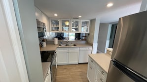 Una cocina moderna con armarios blancos, electrodomésticos de acero inoxidable y piso de madera.