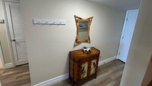Een gang met een houten kast, een spiegel aan de muur en een plafondlamp.