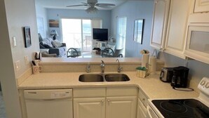 A compact kitchen with a dishwasher, double sink, and stove. - Ocean View Third Floor 2/2 (New Smyrna Beach)