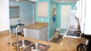 A kitchen with granite countertops, stainless steel appliances, and a window with blinds.