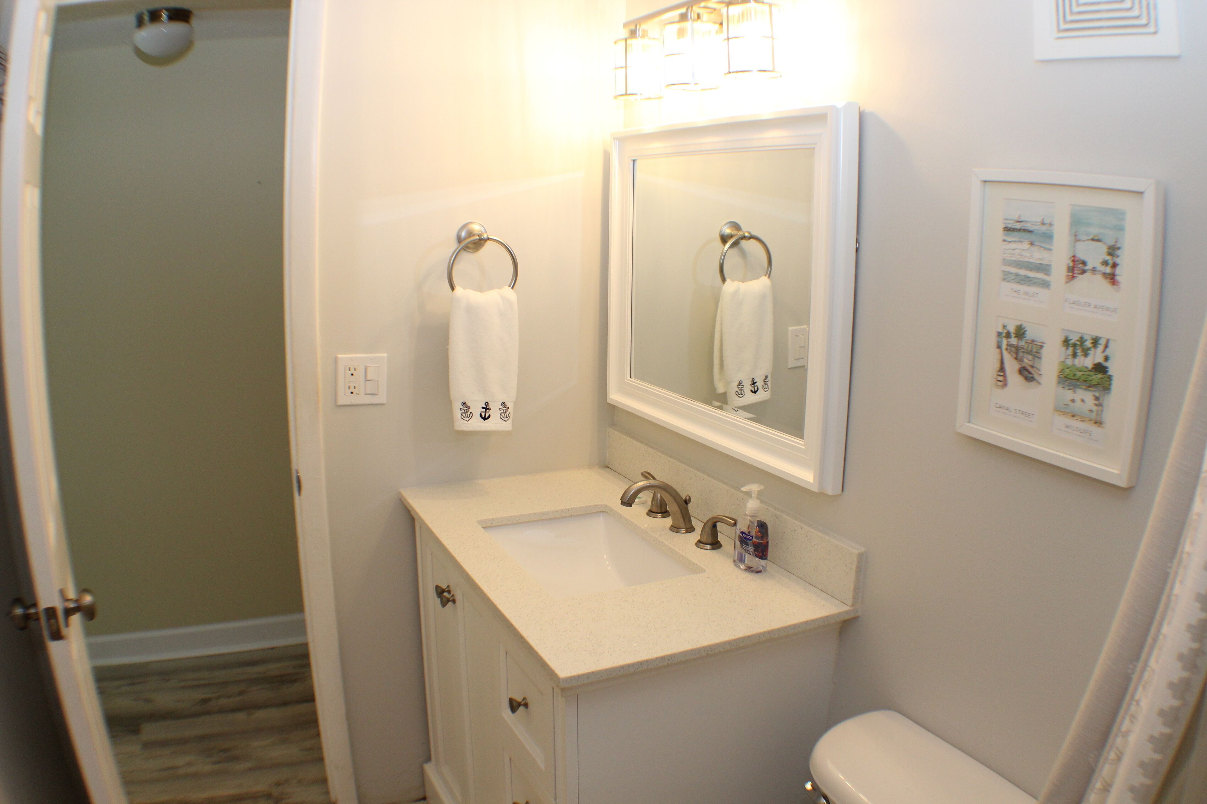 A bathroom with a white sink, a mirror, a toilet, and a shower curtain.