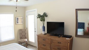 Un dormitorio con una cama, un aparador, un televisor, una silla y una puerta.