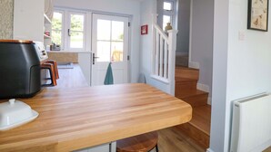 A kitchen with a wooden countertop, a coffee machine, and a view of the outside through a window. - Prospect Cottage (Stone)