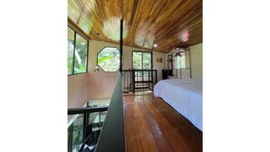 Une pièce avec un plafond en bois, un lit, un balcon et de grandes fenêtres.
