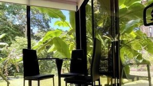 Une pièce moderne avec de grandes fenêtres, deux chaises noires et une table en verre.