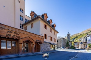 A street with buildings, including a shop with a sign reading "AU FEU DE BOIS".