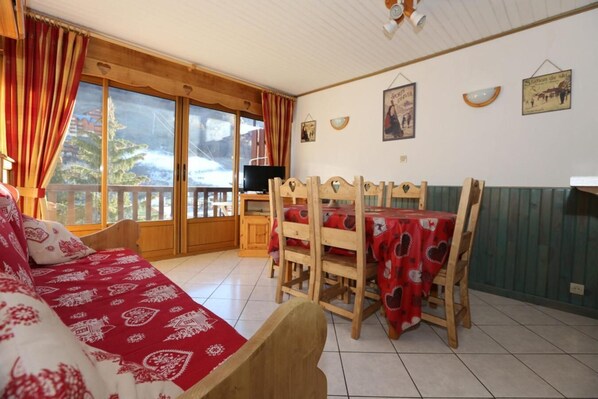 Una habitación acogedora con cama, una mesa de comedor con sillas, televisión y un balcón con vistas al exterior.