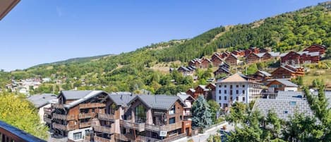 A mountain resort with wooden cabins and modern buildings, featuring balconies and a clear view of the surrounding hills.