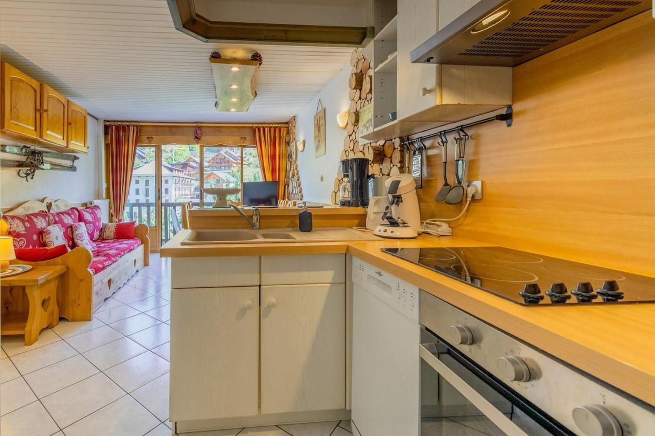 A compact kitchen with a built-in dishwasher, a stove, and a coffee machine.
