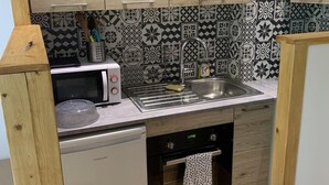 Eine kleine Küche mit Holzausstattung, einer Mikrowelle, einem Spülbecken und einem Geschirrspüler.
