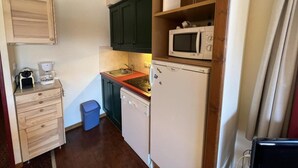 A compact kitchen with a microwave, coffee maker, and a small sink.