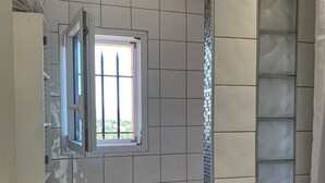 A bathroom with white tiles, a window, a shower curtain, and a bathtub. - A balcony overlooking the magnificent ochre cliffs of Roussillon (Roussillon)