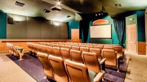 A theater with rows of seats, a screen, and a stage area.