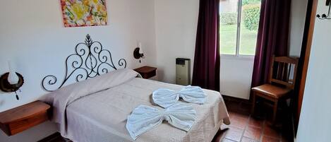 Un dormitorio con cama, techo de madera, ventana con cortinas, una silla y aire acondicionado instalado en la pared.