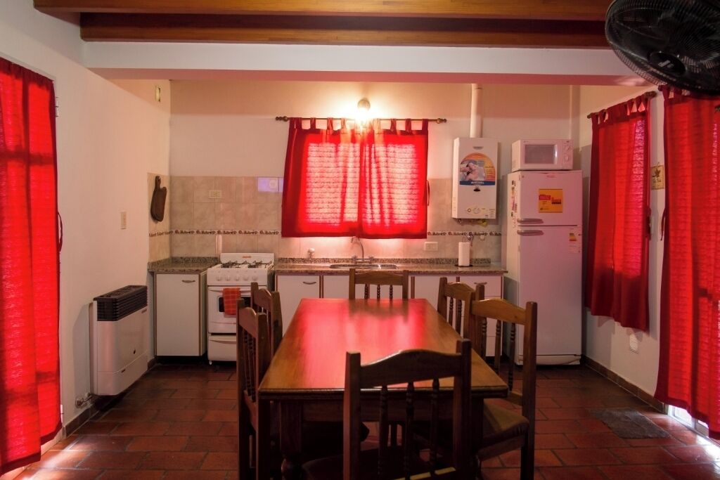 Cocina compacta con una mesa de comedor, sillas, refrigerador, microondas y estufa.