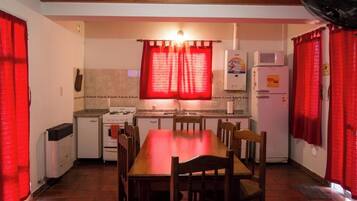 Une cuisine compacte comprenant une table à manger, des chaises, un réfrigérateur, un four à micro-ondes et une cuisinière.