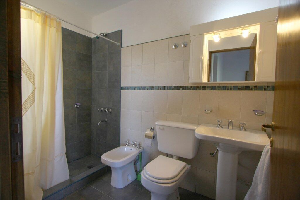 Une salle de bain équipée d’une douche, d’un bidet, de toilettes, d’un lavabo et d’un miroir avec éclairage.